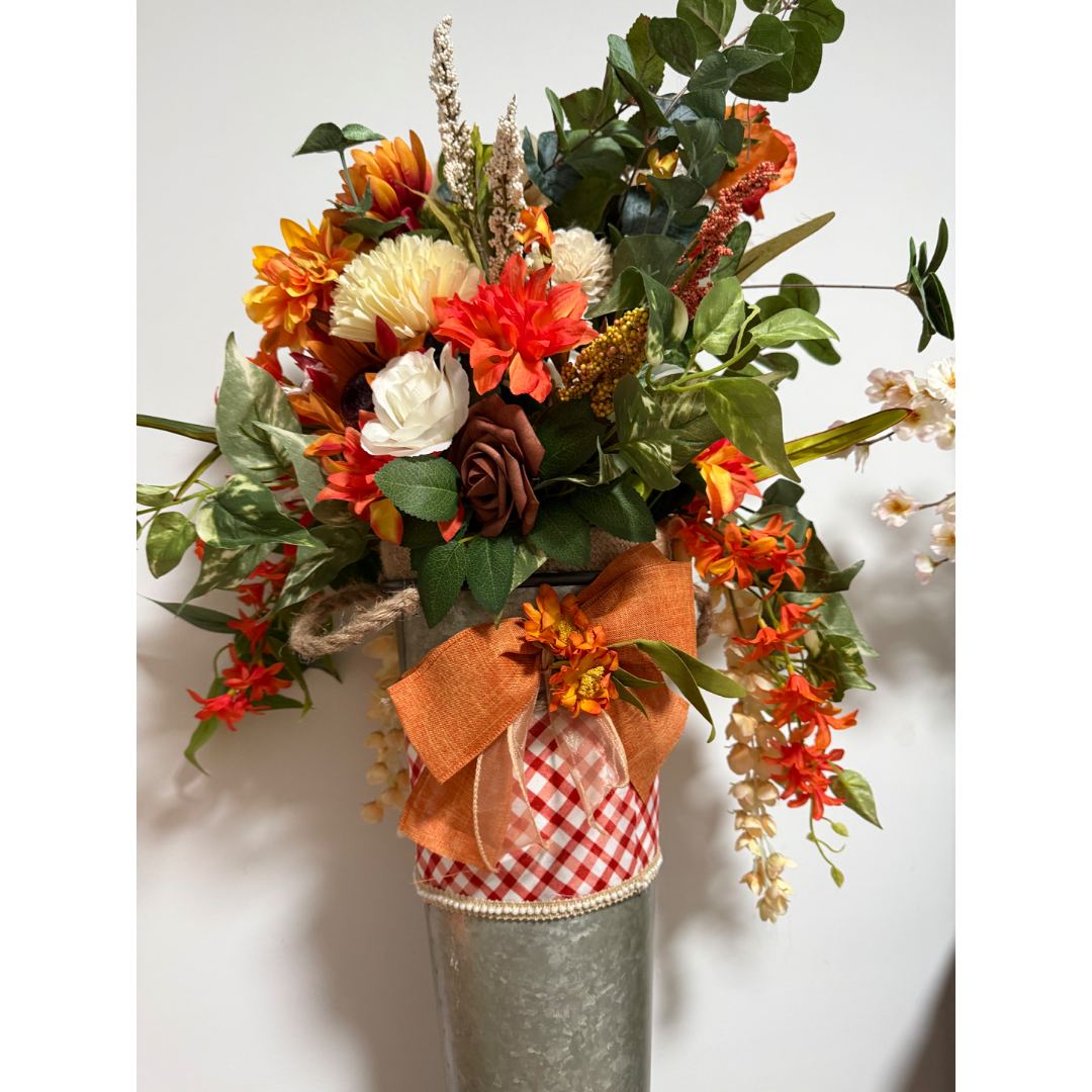 Autumn floral arrangement in a tall metal vase with orange and white blooms