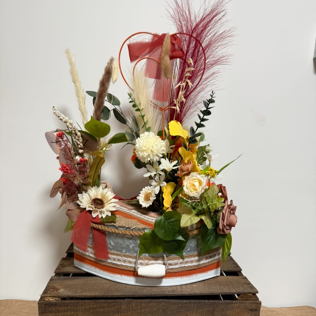 Mixed floral arrangement in a decorated round container with tall dried accents