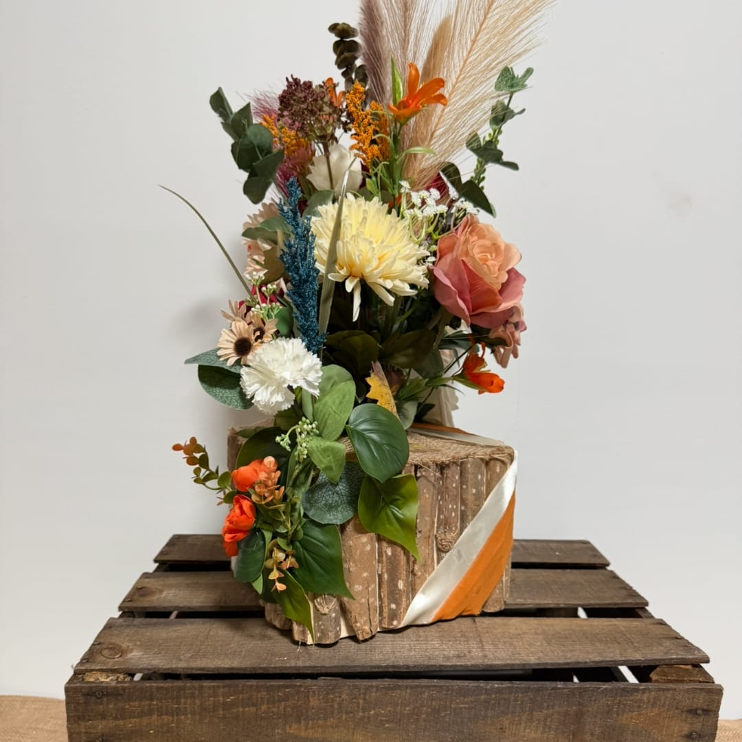 Tall mixed floral arrangement in a rustic wood container with orange and cream blooms