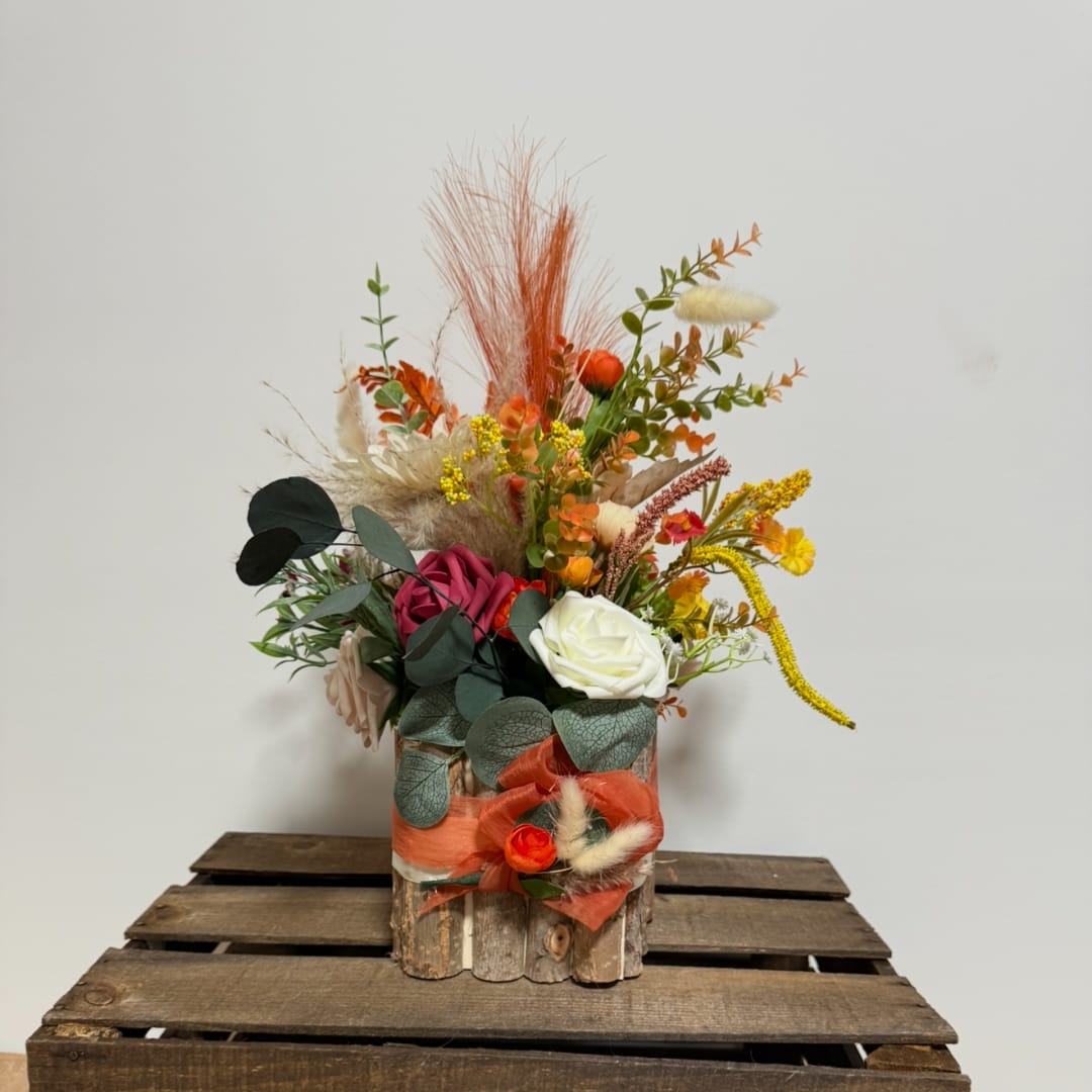 Colorful floral arrangement in a rustic wooden container with orange and white blooms