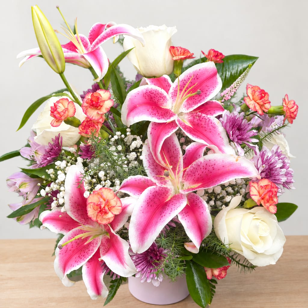 Pink lilies and white roses arranged in a pale vase