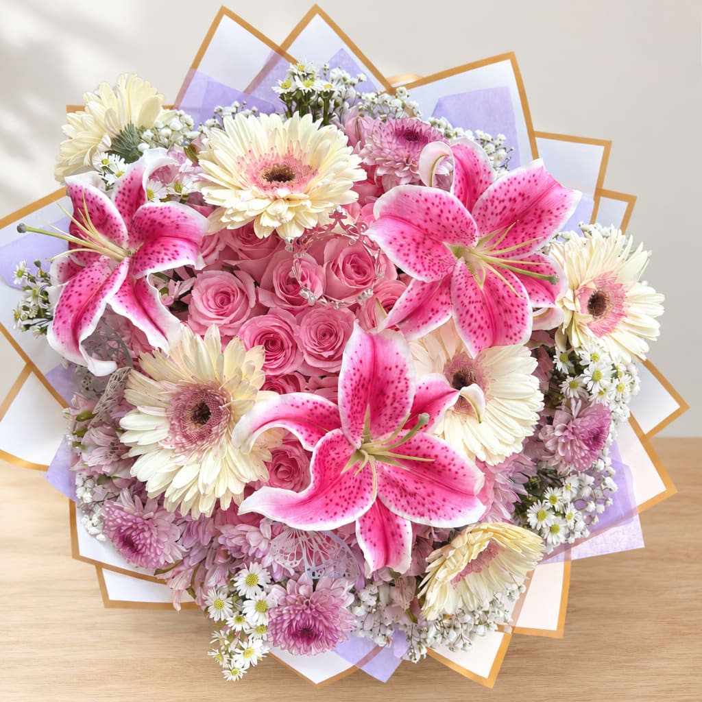 Pink lilies and roses with cream gerbera daisies in a wrapped bouquet