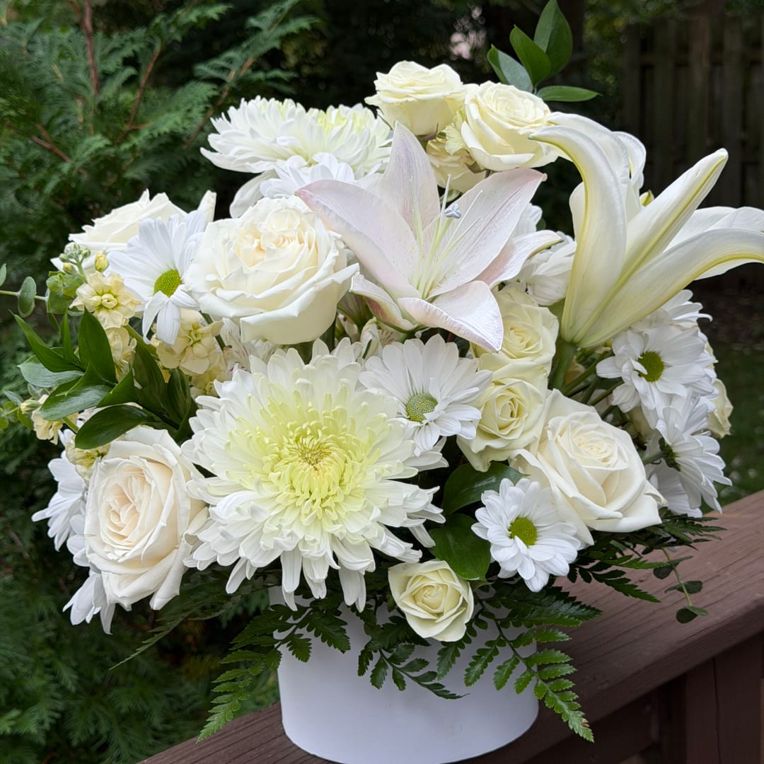 White roses and lilies arranged in a white vase with daisies and chrysanthemums