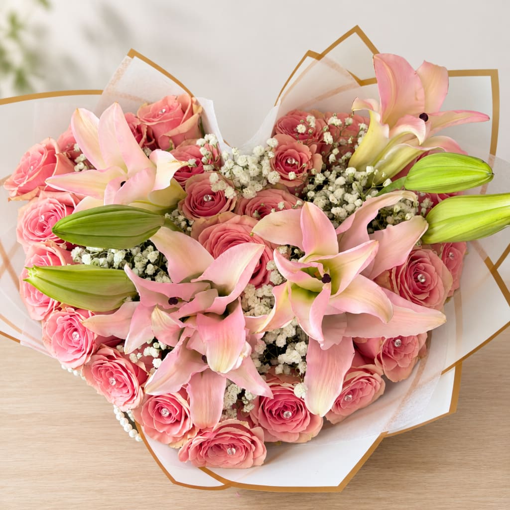 Pink roses and lilies arranged in a wrapped bouquet