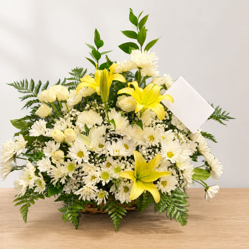 White and yellow floral arrangement in a basket with a blank card