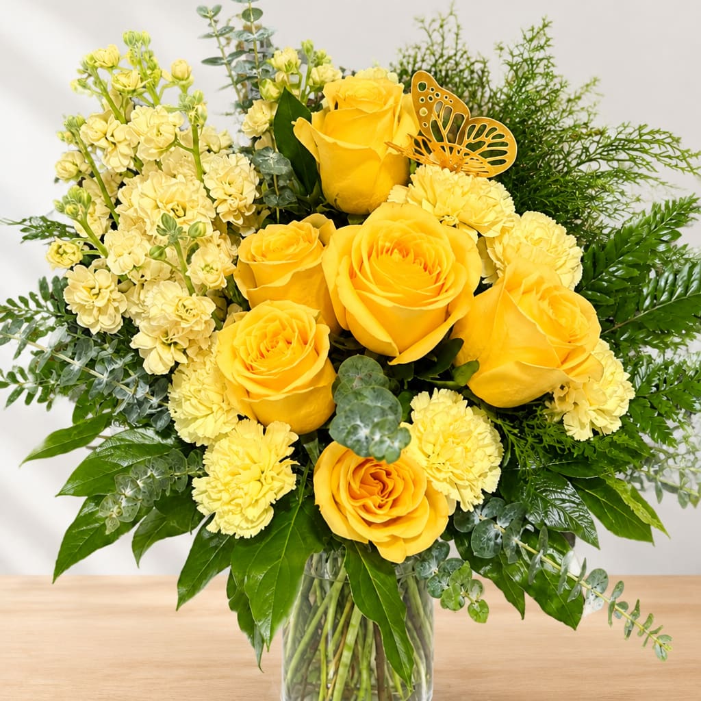 Yellow roses and pale yellow flowers in a clear glass vase
