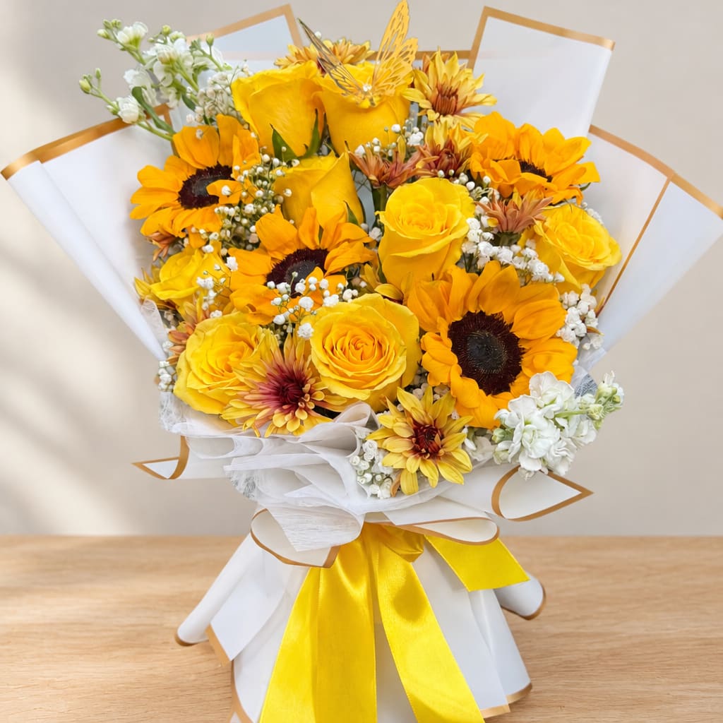 Yellow roses and sunflowers wrapped in white paper with a yellow ribbon