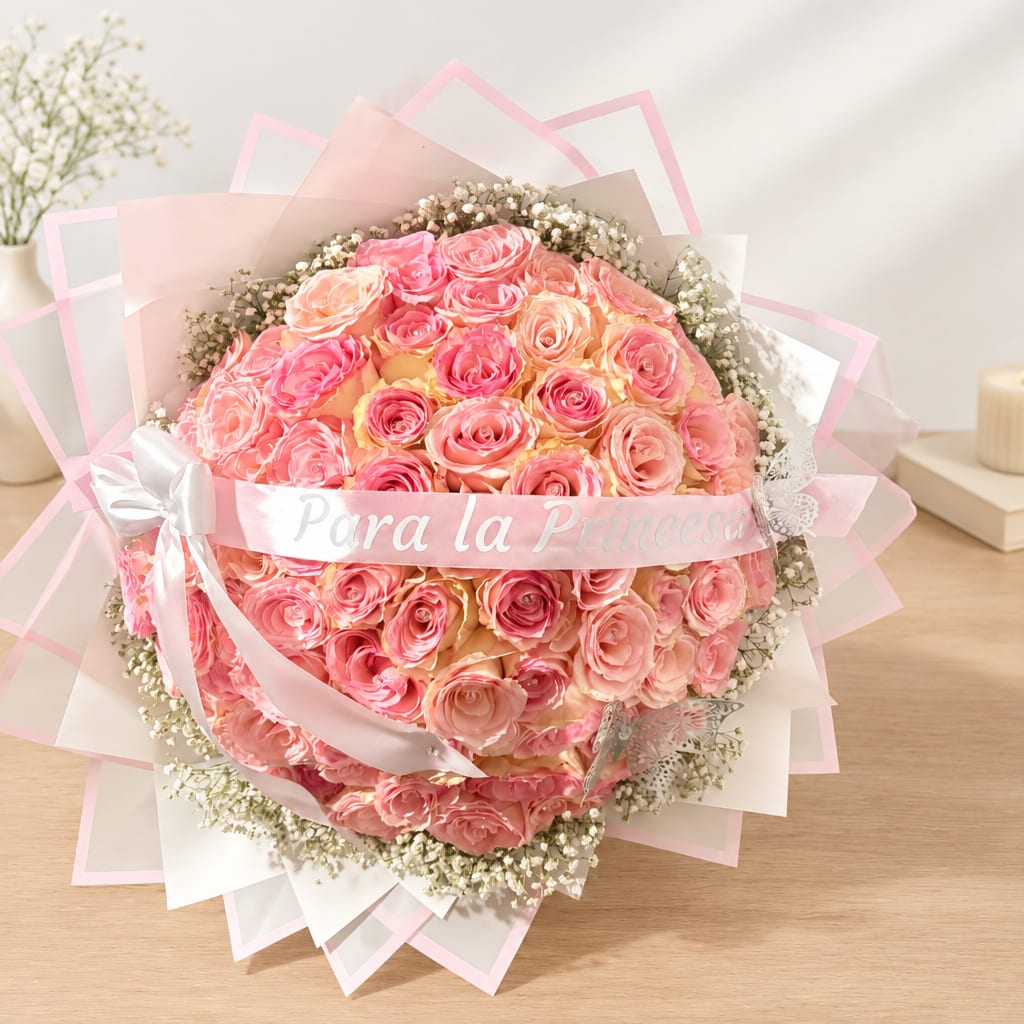 Round bouquet of pink and peach roses wrapped in pink paper with a ribbon