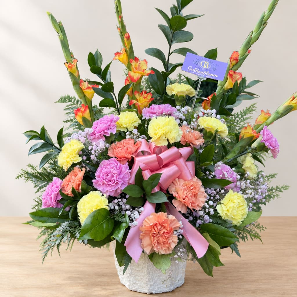 Colorful floral arrangement in a white vase with a pink ribbon bow