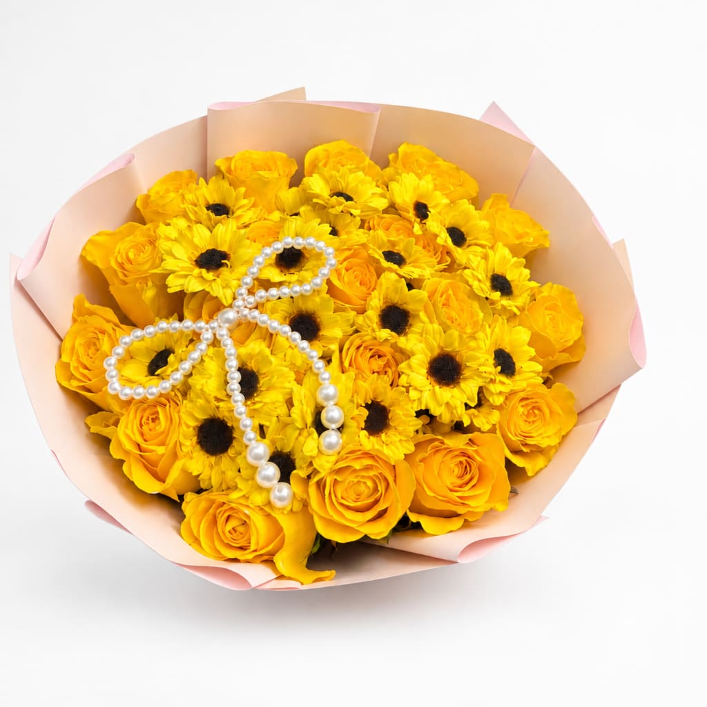 Yellow roses and daisy-like flowers wrapped in pale pink paper with a pearl ribbon