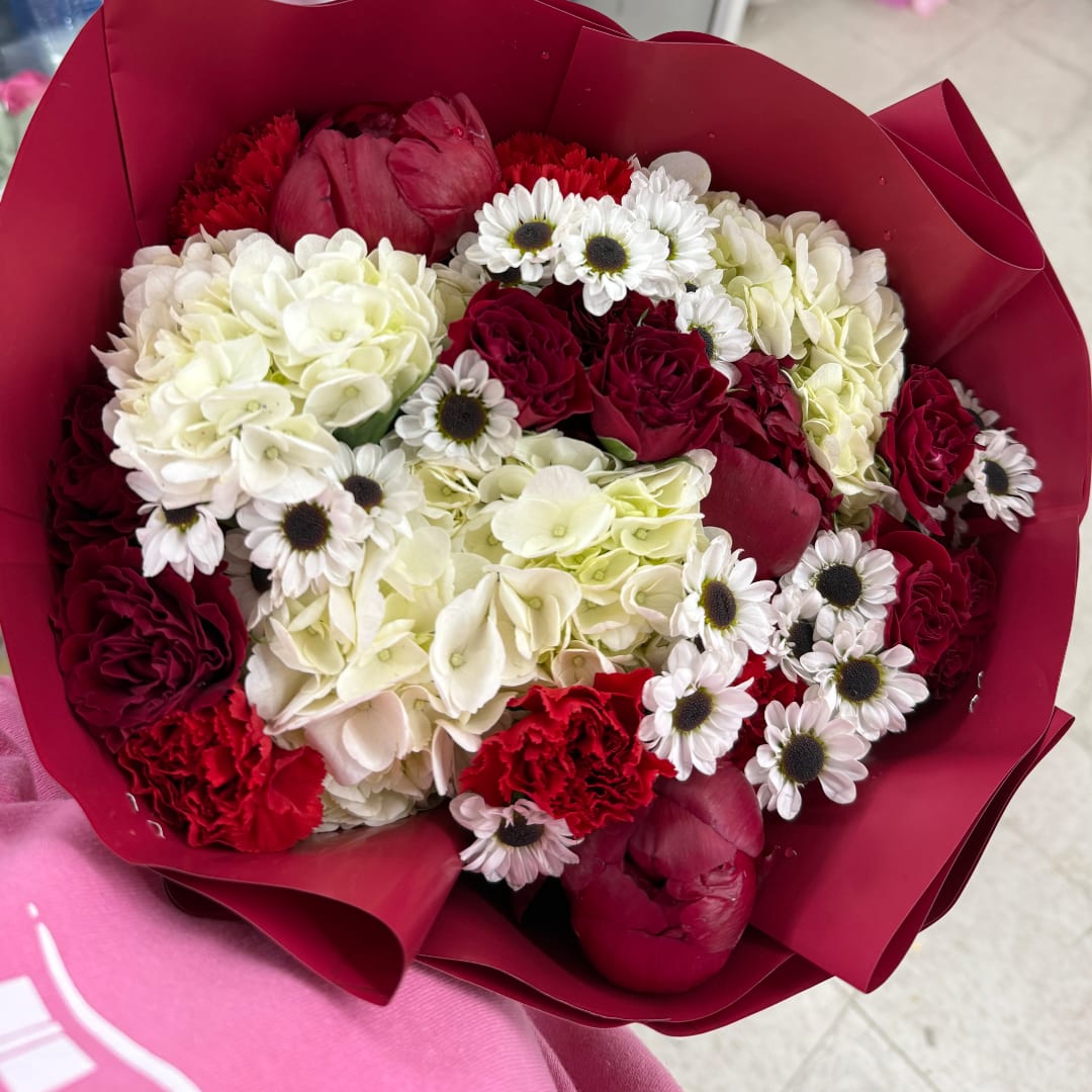 Bouquet of red and white flowers wrapped in burgundy paper