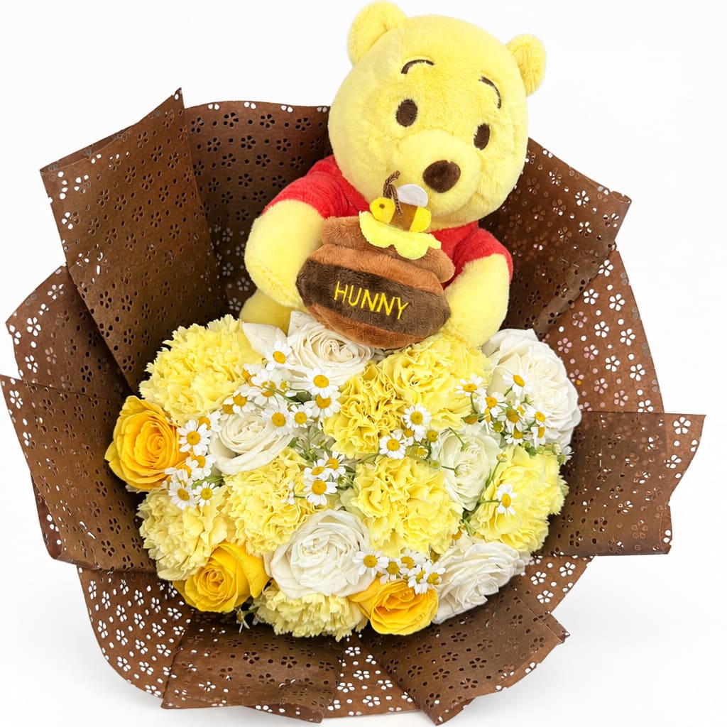 Yellow teddy bear holding a honey pot above a bouquet of yellow and white flowers