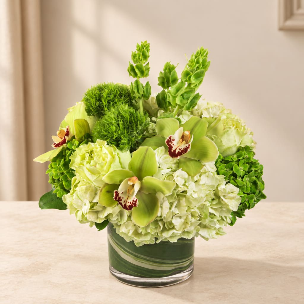 Green and white floral arrangement in a glass vase