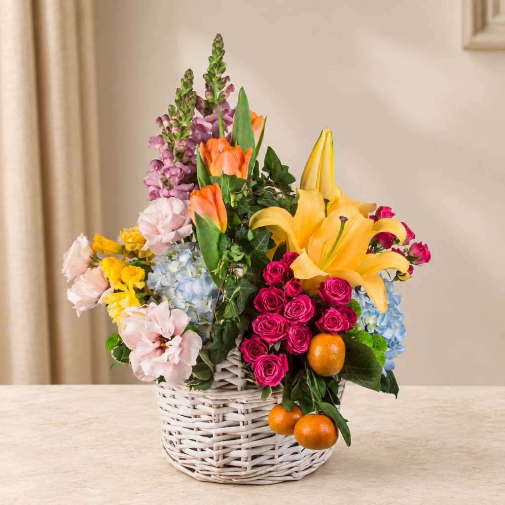 Mixed flower basket with lilies, roses, hydrangeas, and oranges
