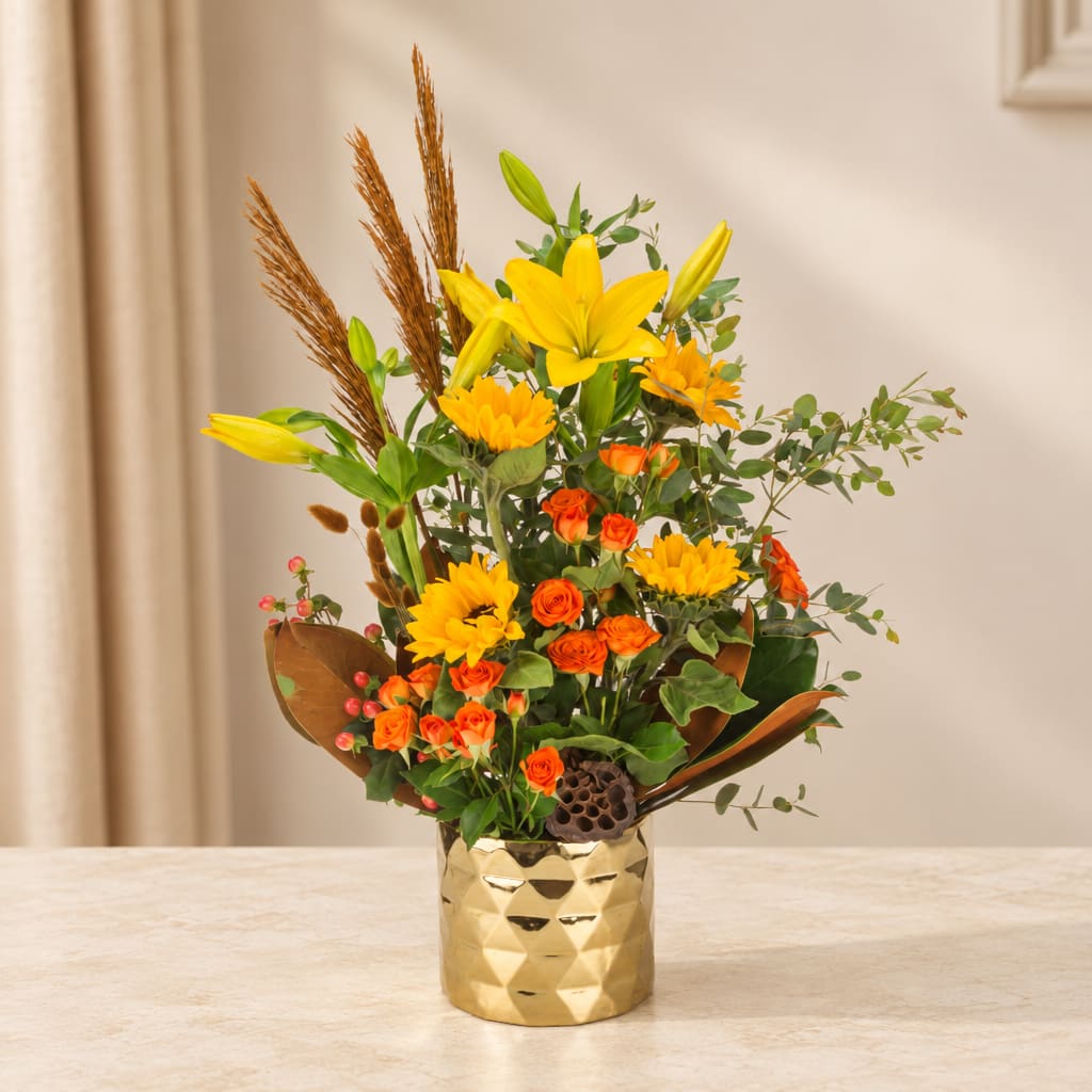 Yellow lilies and orange roses in a gold vase