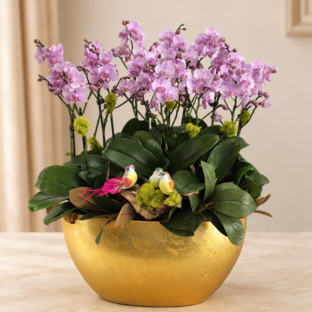 Pink orchids in a gold bowl planter with small bird figurines