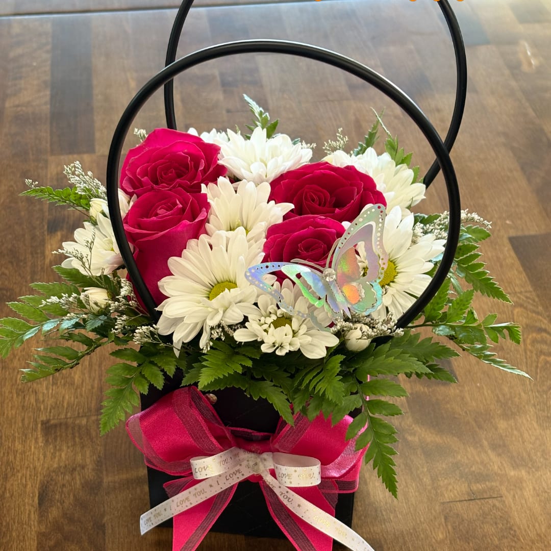 Pink roses and white daisies in a black handled basket with a butterfly pick