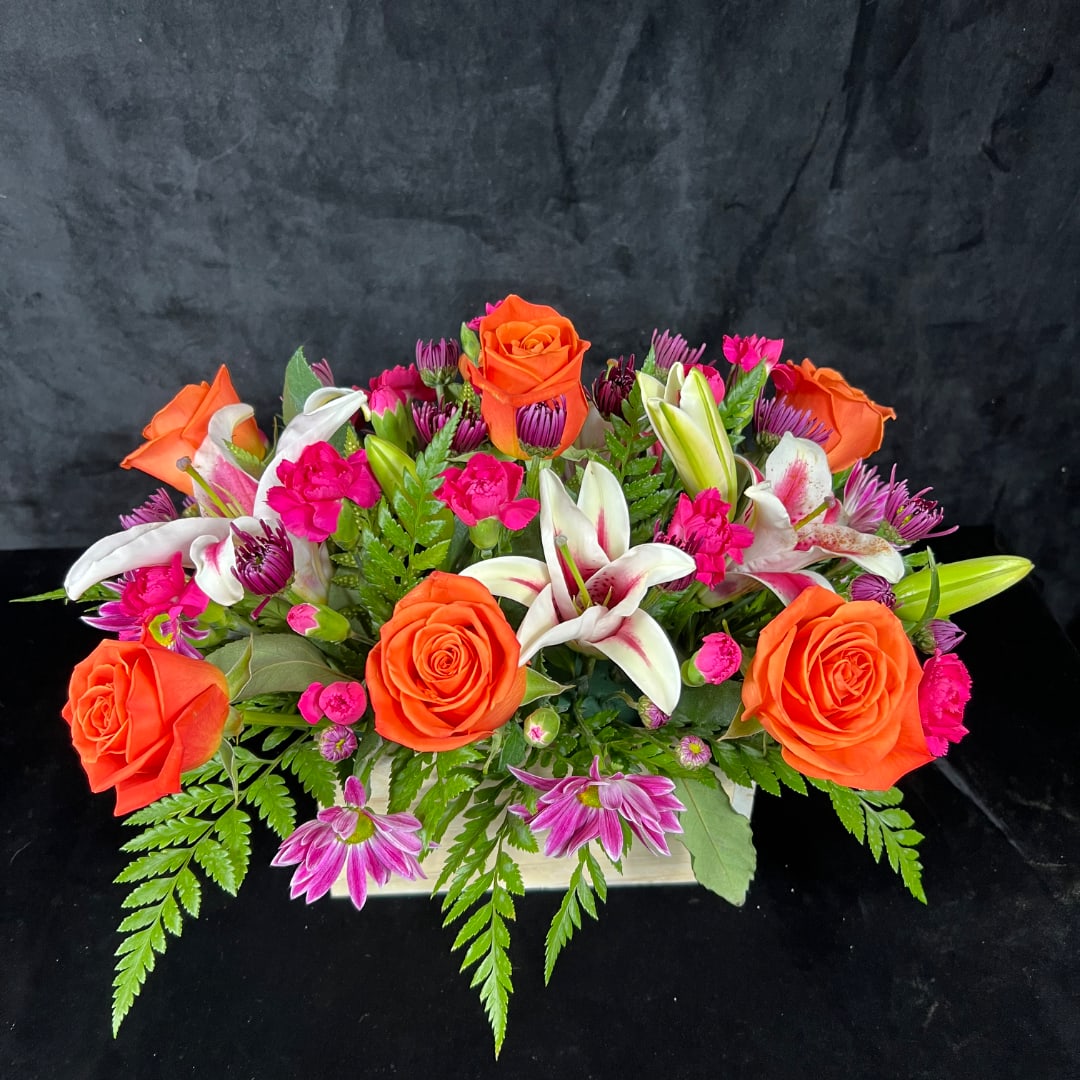 Orange roses and white lilies in a low rectangular arrangement