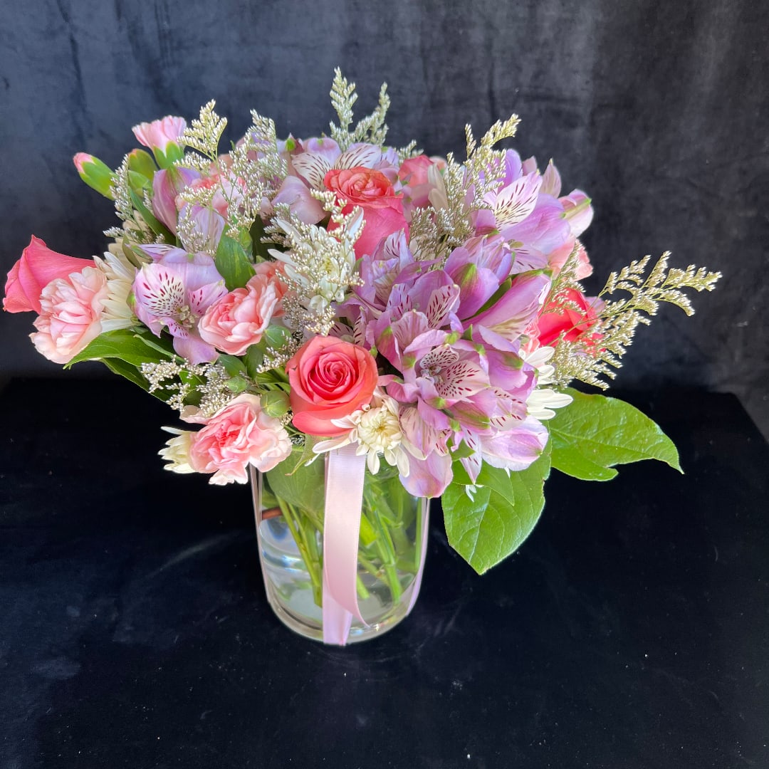 Pink and lavender mixed bouquet in a clear glass vase with a ribbon