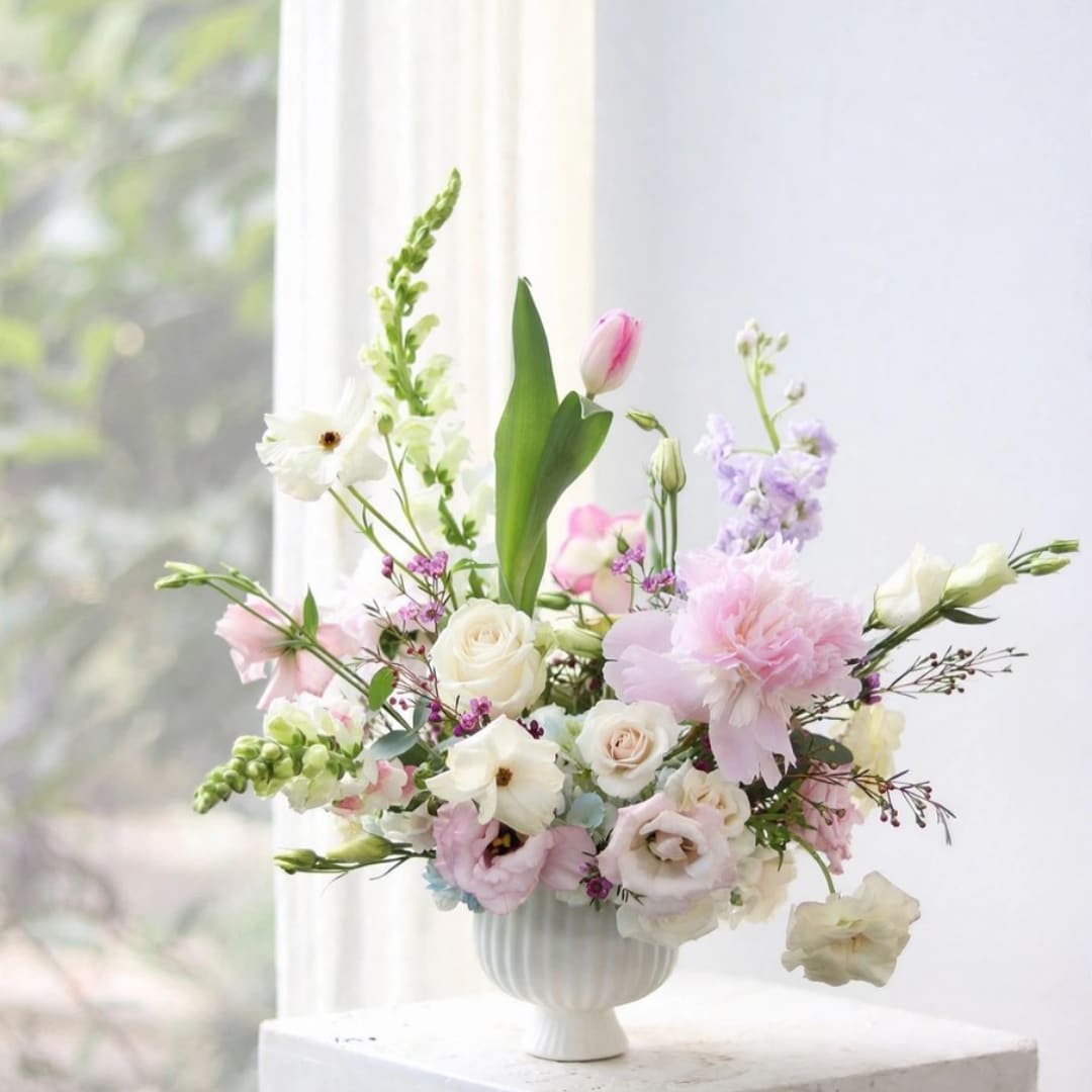 Pastel floral arrangement in a white vase with roses and tulips