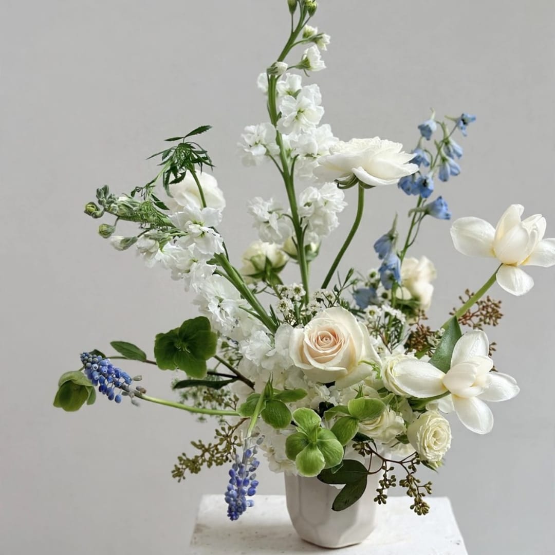 White and blue floral arrangement in a white vase