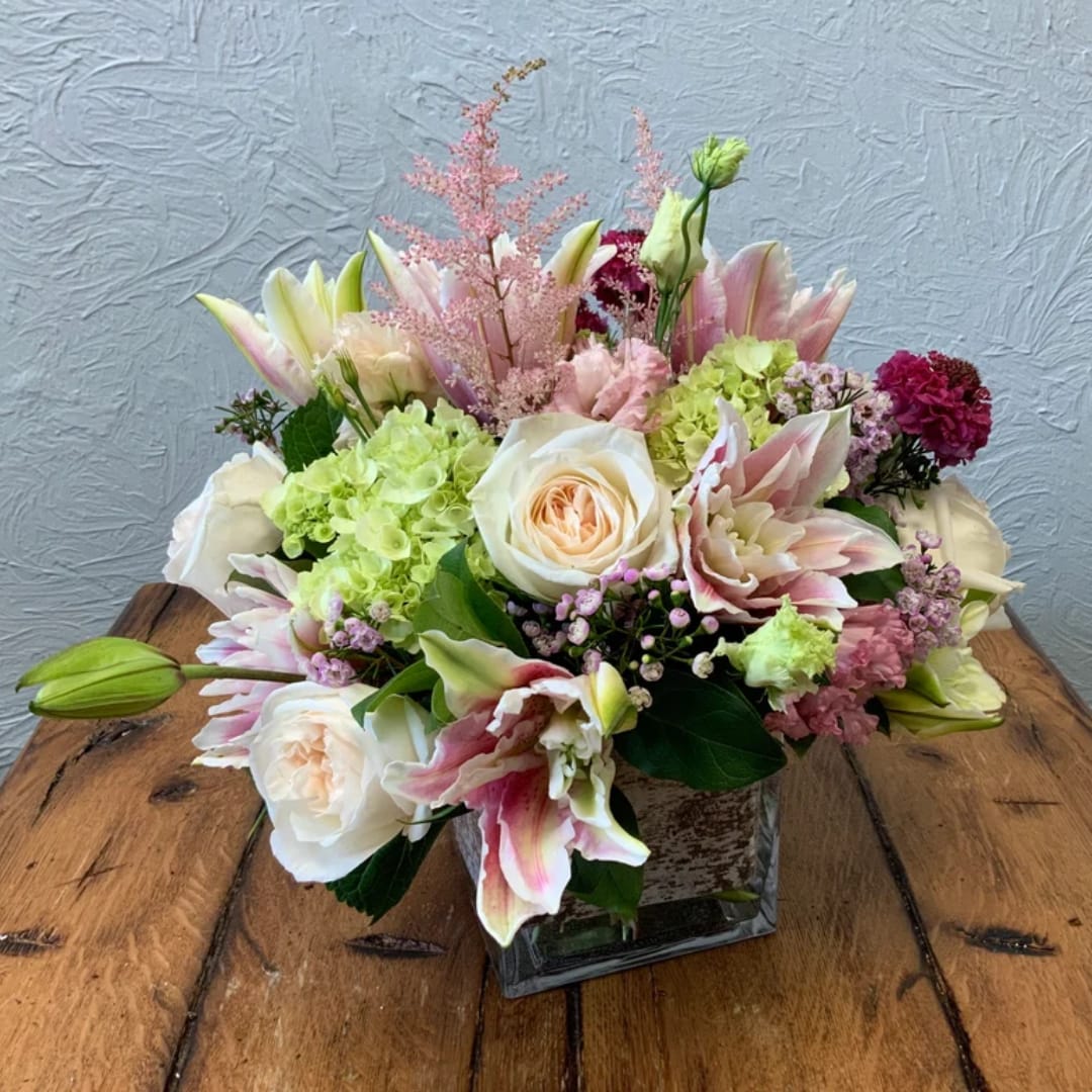 Pink and white floral arrangement in a square glass vase