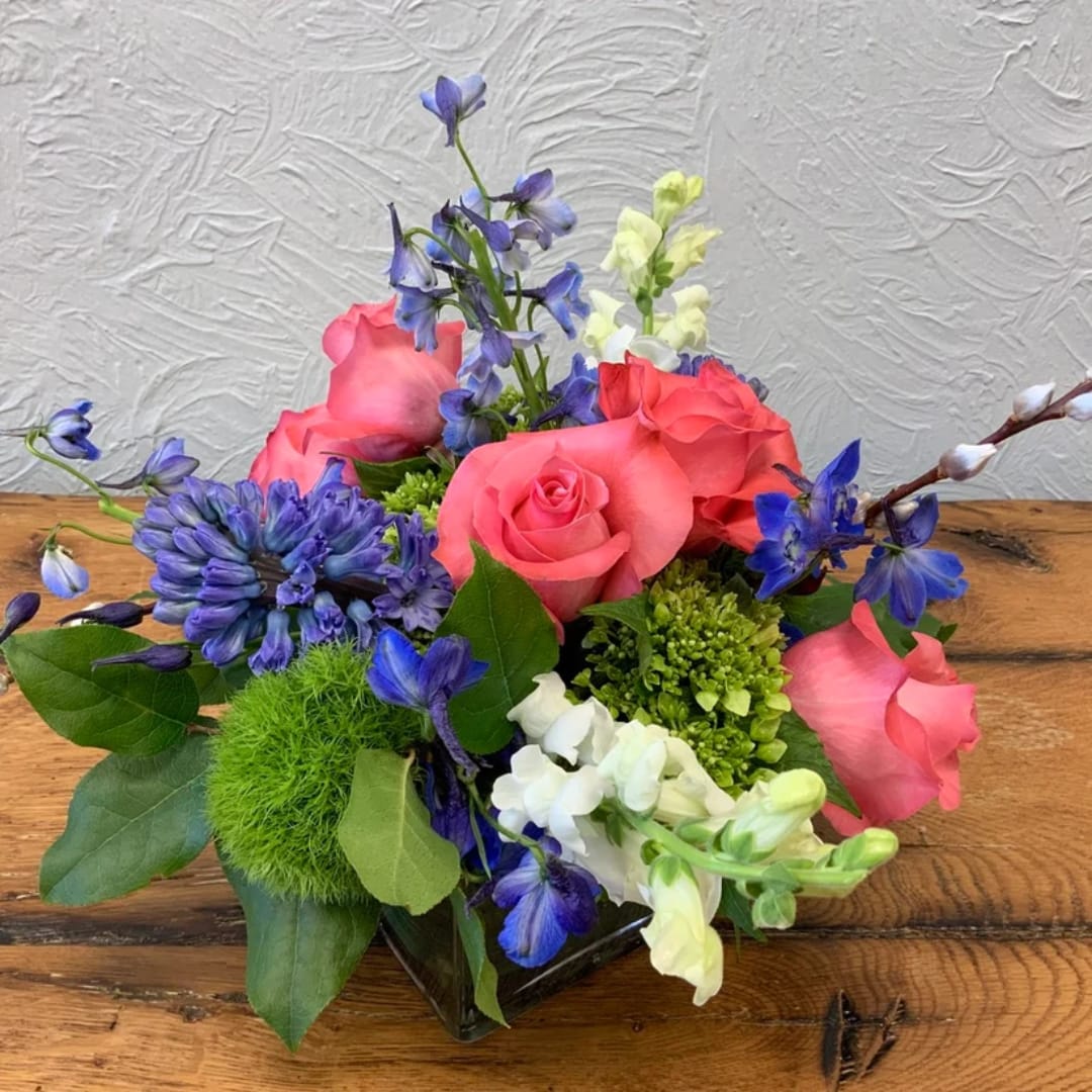 Pink roses and blue-purple flowers in a low glass vase