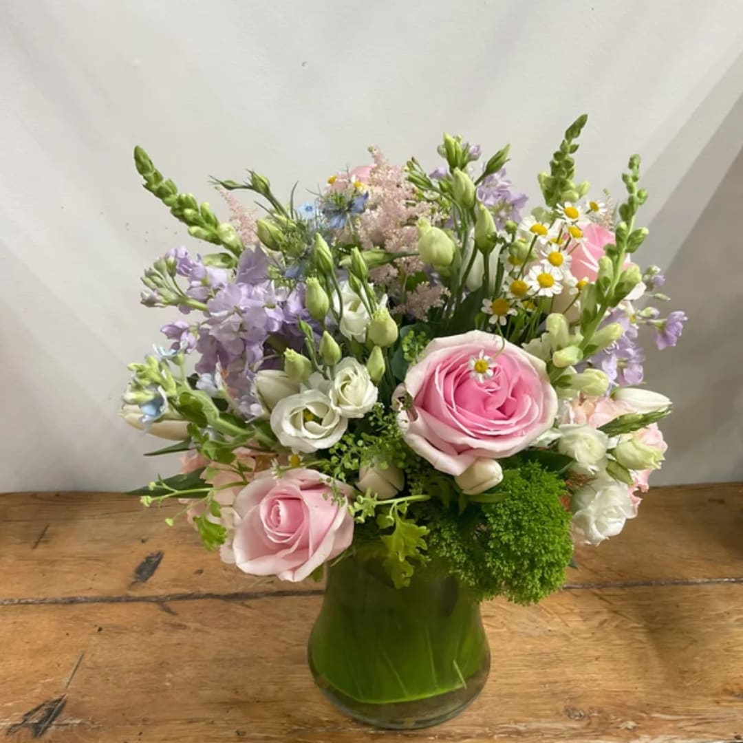 Pink roses and mixed pastel flowers in a green glass vase
