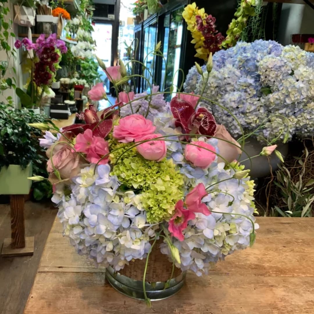 Pink roses and blue hydrangeas arranged in a low glass vase