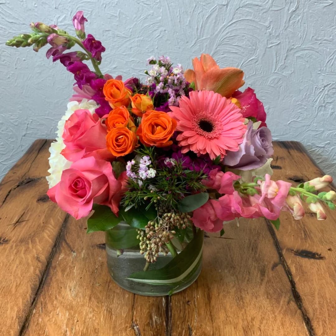 Colorful mixed bouquet in a glass vase with pink and orange blooms