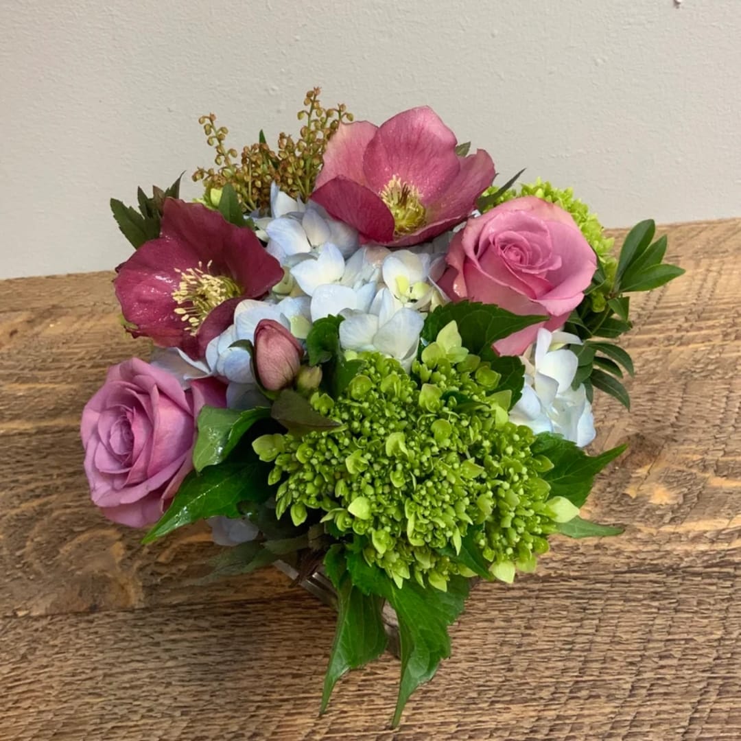 Pink roses and hydrangeas with dark hellebore blooms in a low bouquet