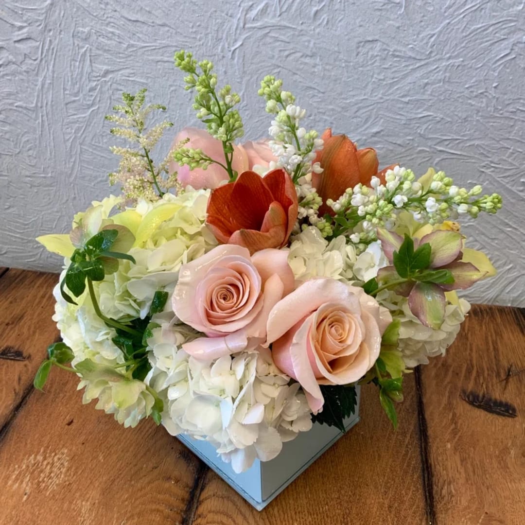 Compact floral arrangement with pale pink roses and white hydrangeas in a square vase