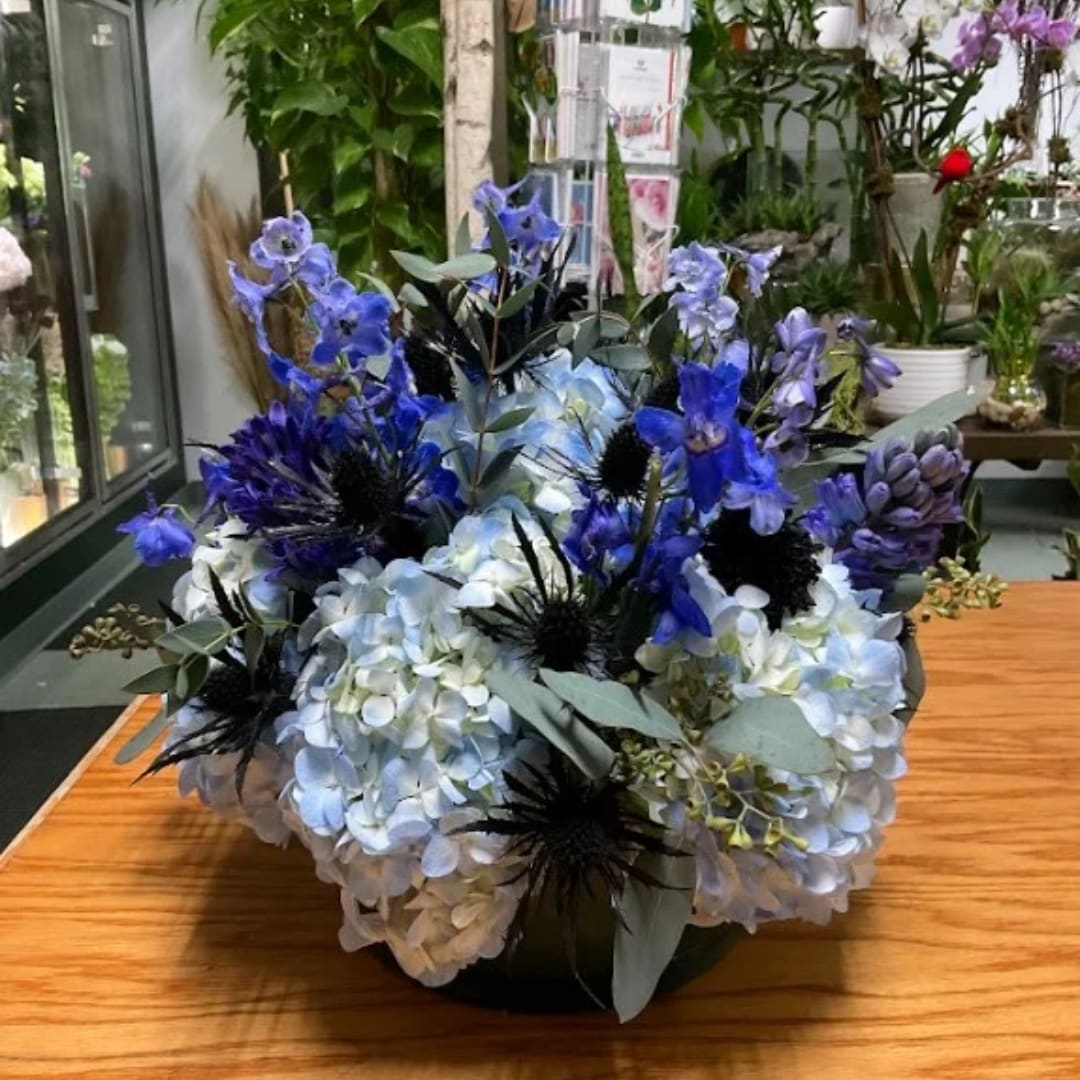 Blue and white floral arrangement in a low container