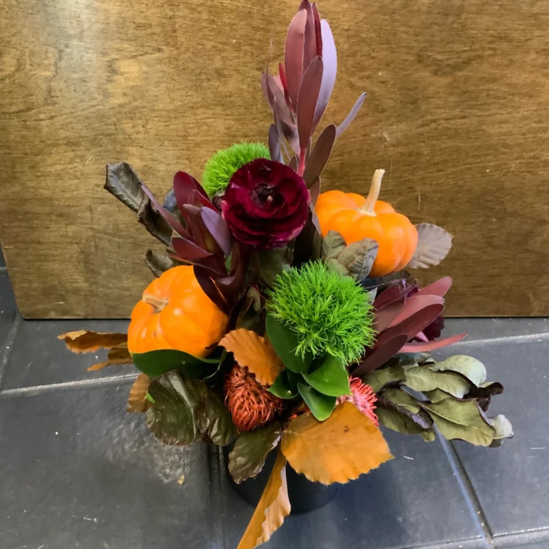 Autumn floral arrangement with pumpkins in a black container
