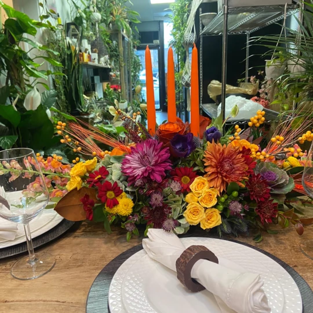 Colorful floral centerpiece with orange taper candles on a table
