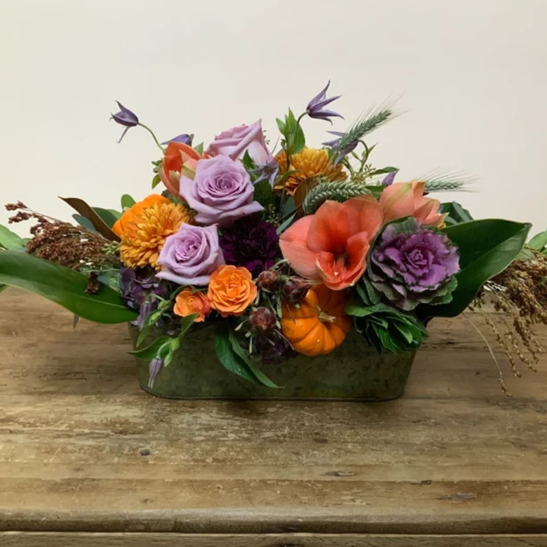 Mixed bouquet in a low rectangular vase with purple, orange, and peach flowers
