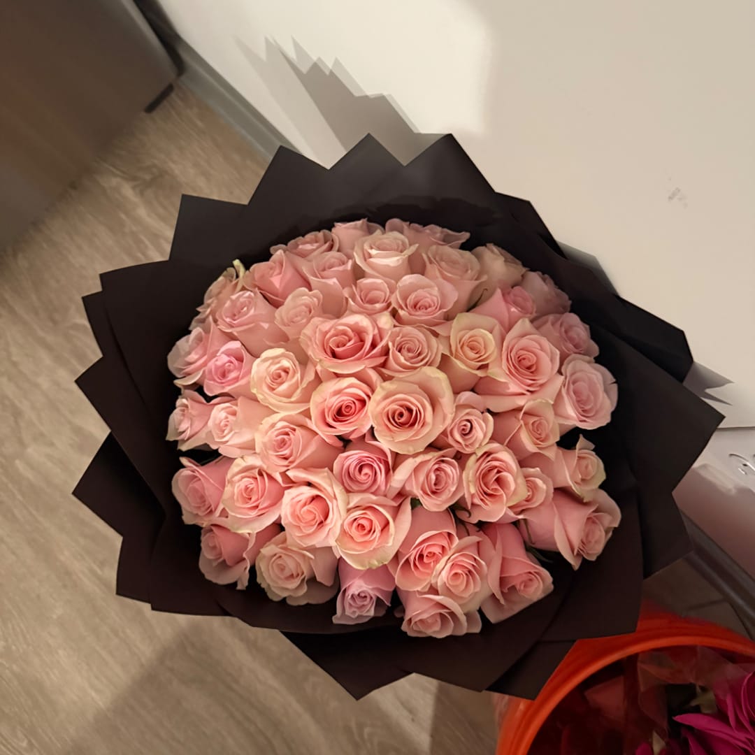 Bouquet of pale pink roses wrapped in black paper