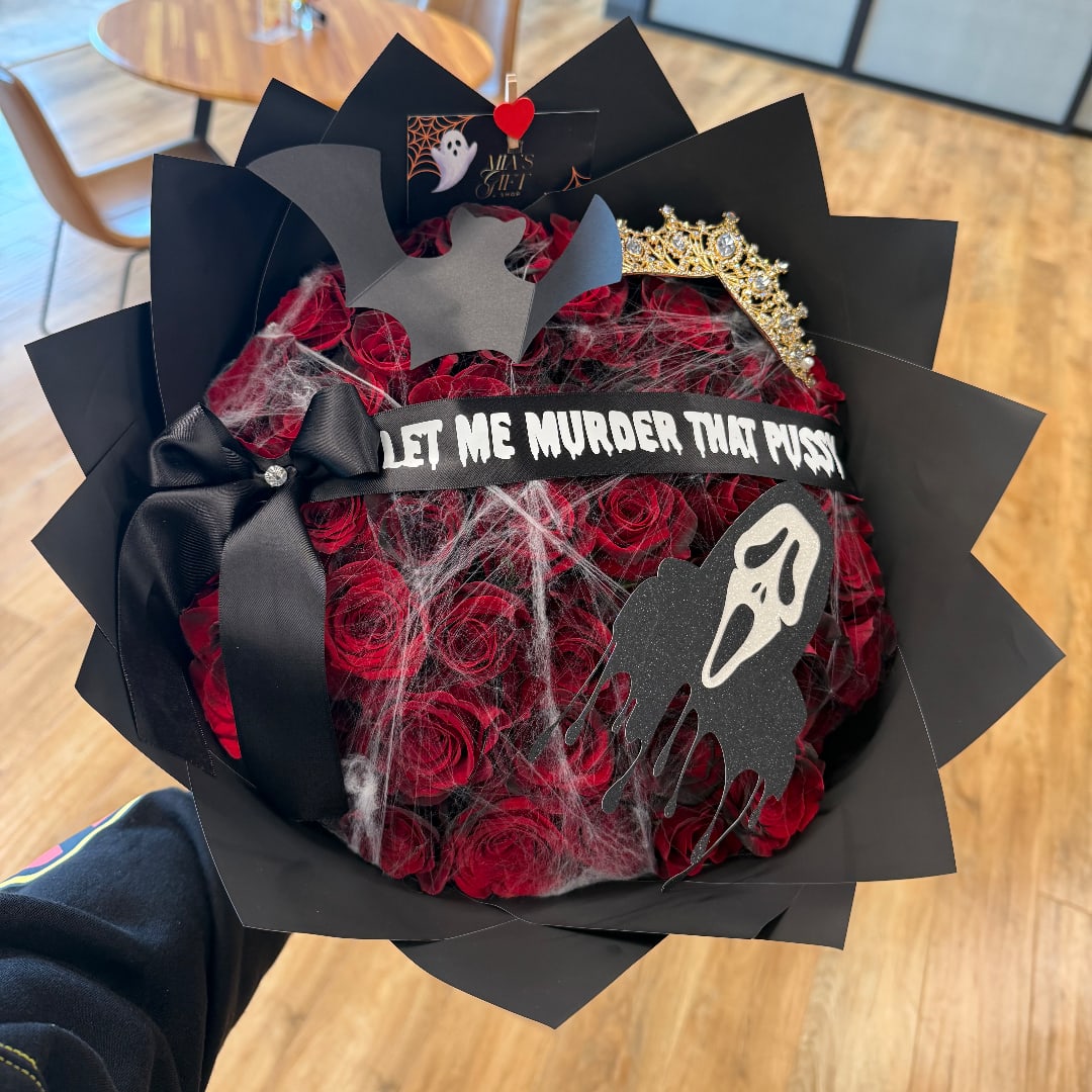 Bouquet of red roses wrapped in black paper with Halloween decorations