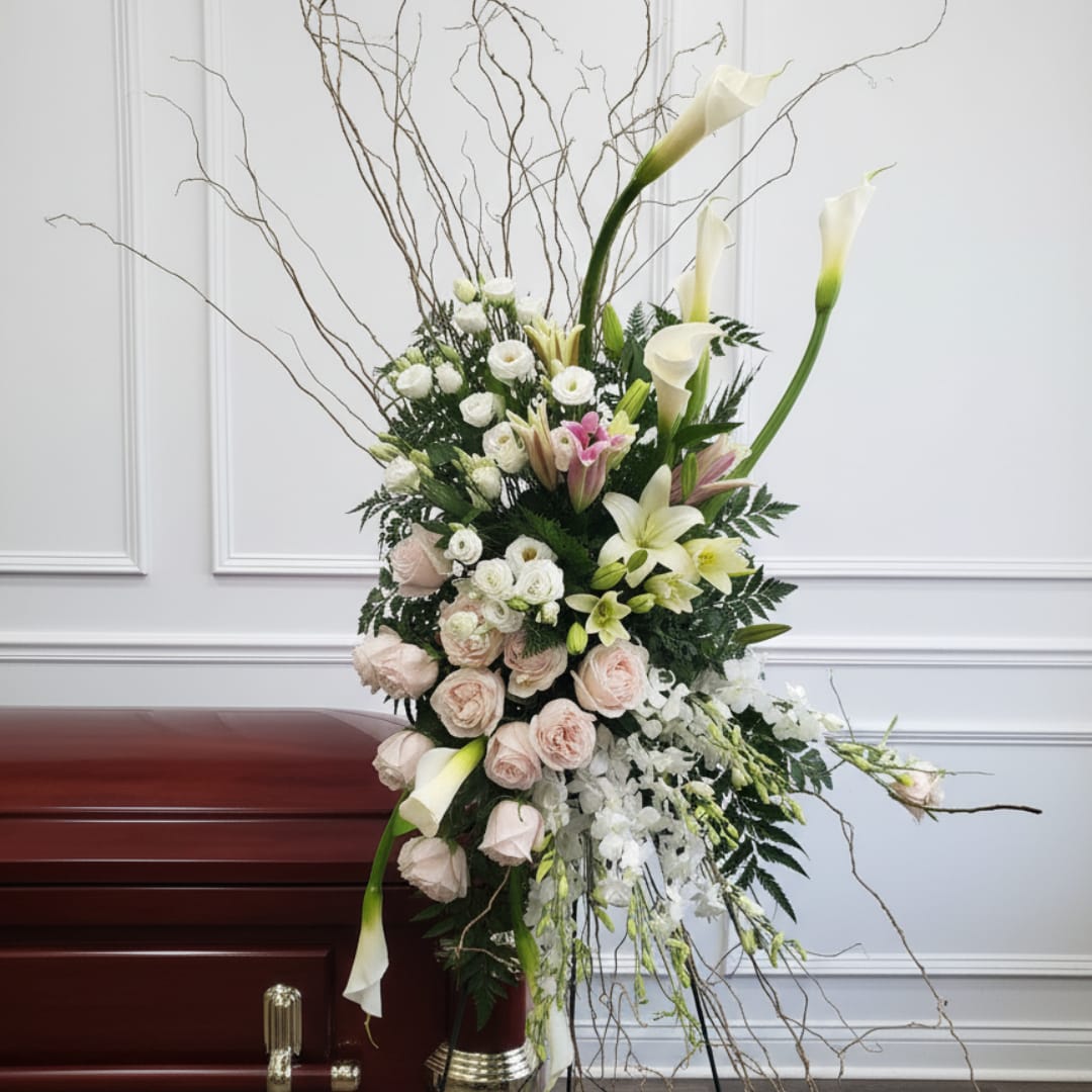 Tall floral arrangement with white calla lilies, pale roses, and pink accents