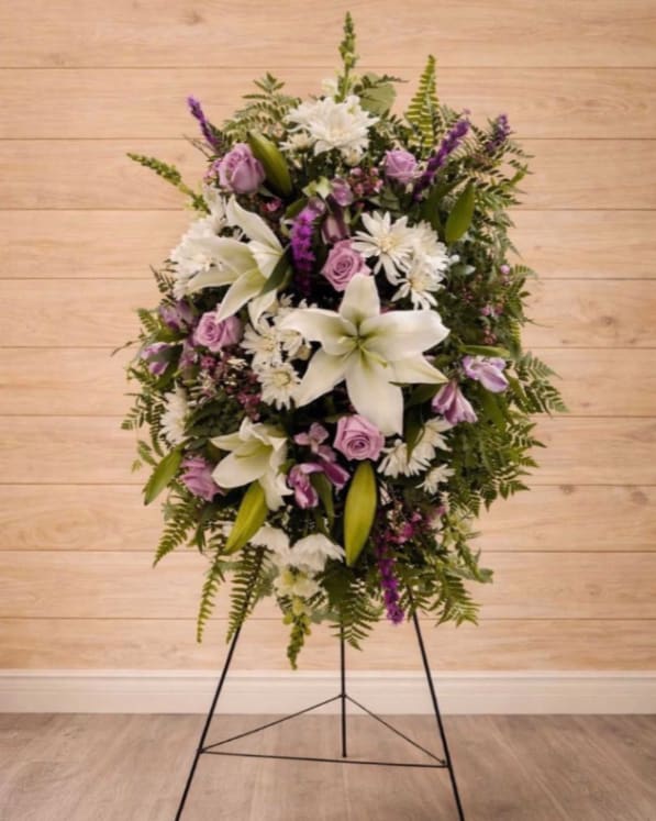 Standing floral wreath with white lilies, lavender roses, and purple accents