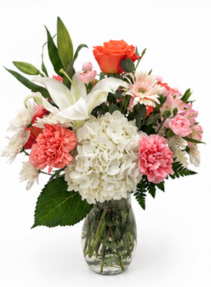 Mixed bouquet of lilies, roses, hydrangea, and carnations in a glass vase