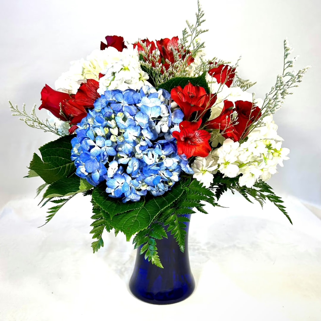 Red, white, and blue flower arrangement in a blue vase