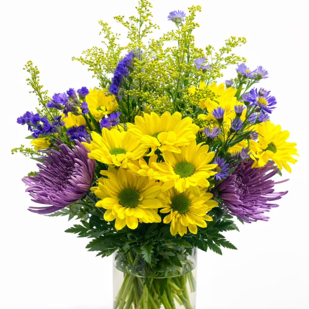 Yellow and purple flowers arranged in a clear glass vase