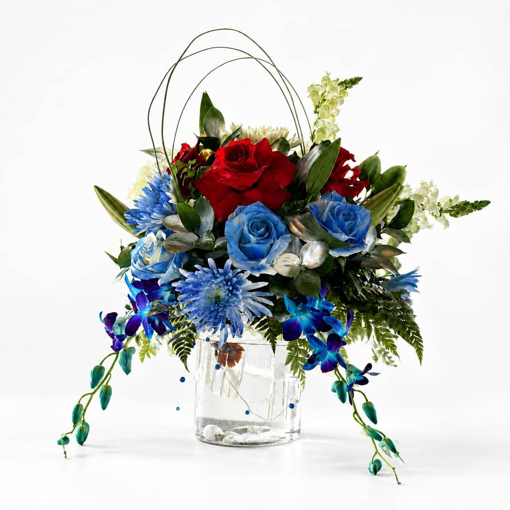 Red and blue roses in a clear glass vase with trailing orchids