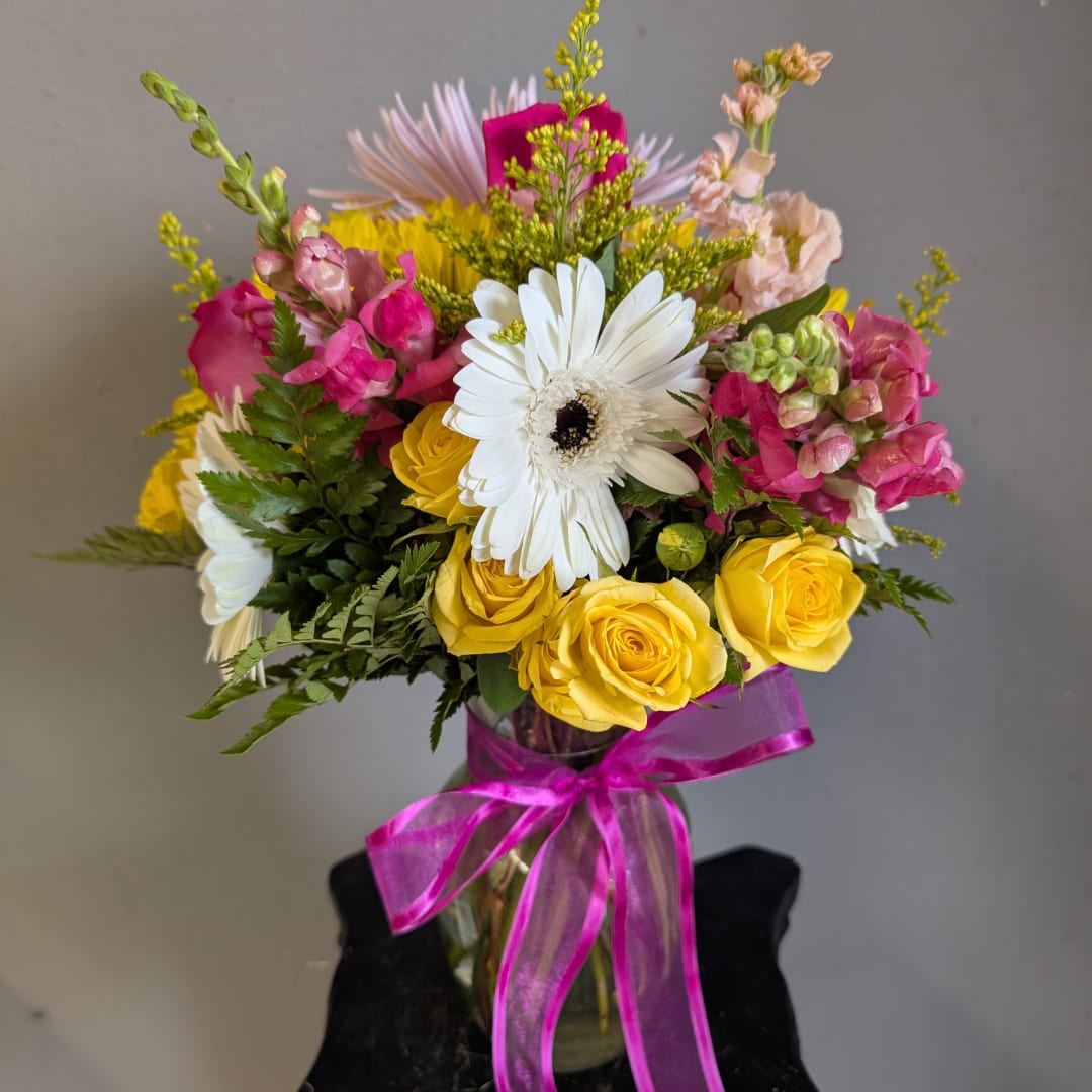 Mixed bouquet of yellow roses, white gerbera daisies, and pink snapdragons in a glass vase