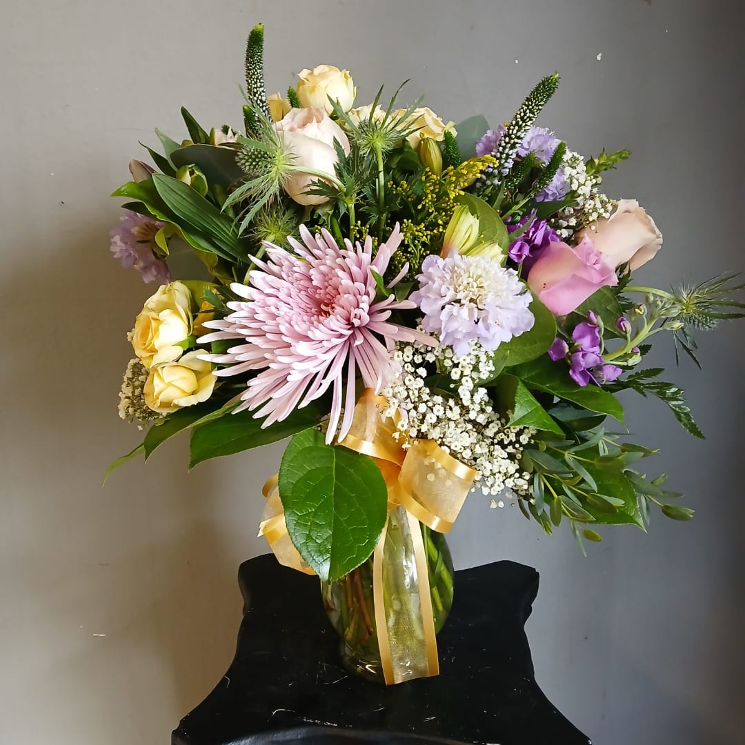 Mixed bouquet in a glass vase with pink, yellow, and purple flowers