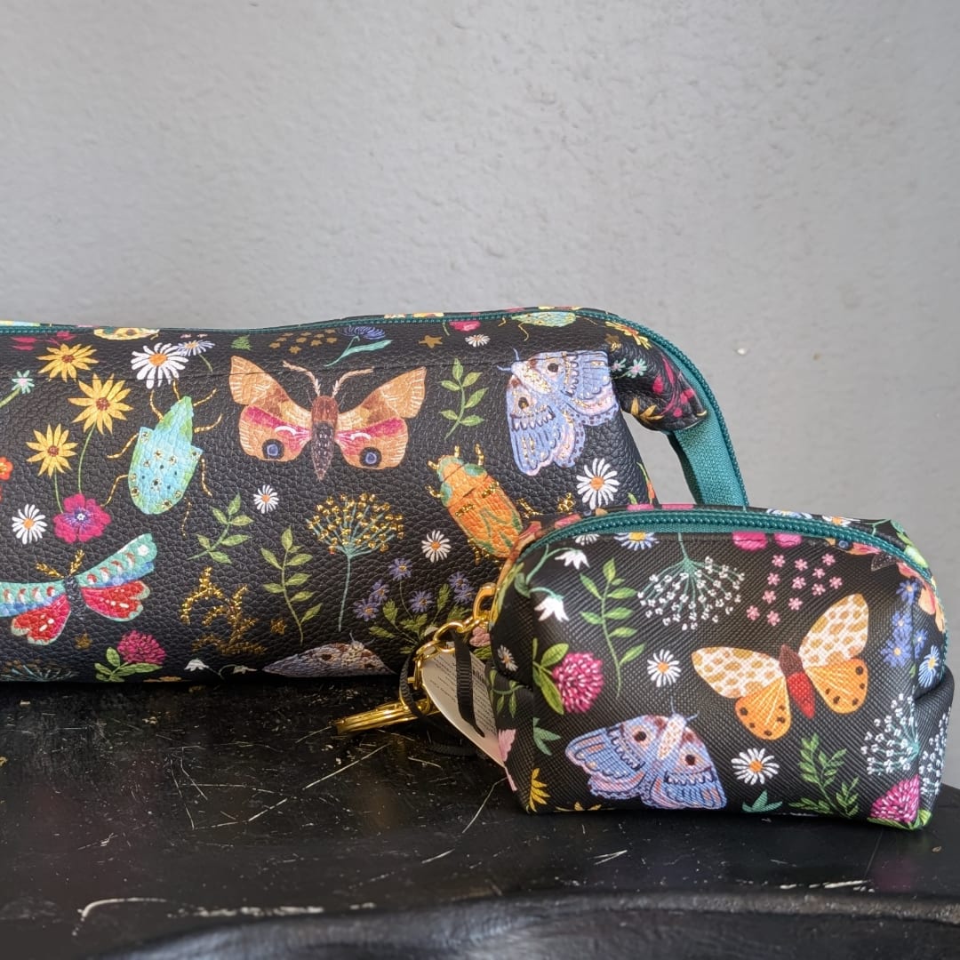 Butterfly-print cosmetic bag and matching pouch on a dark surface