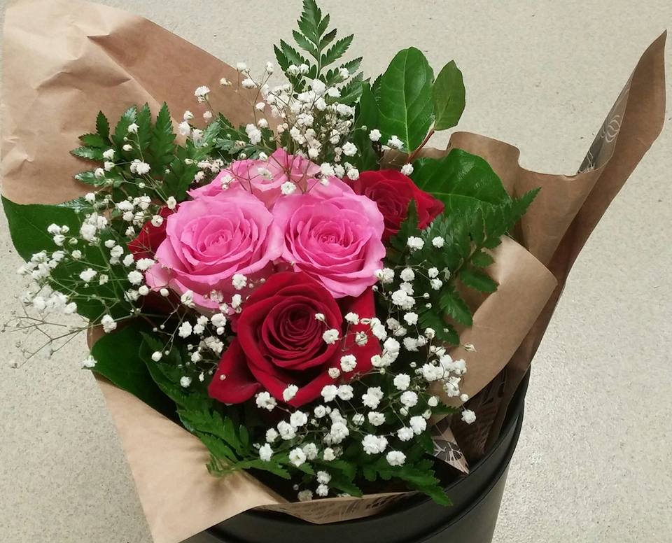 Bouquet of pink and red roses with baby's breath in brown paper