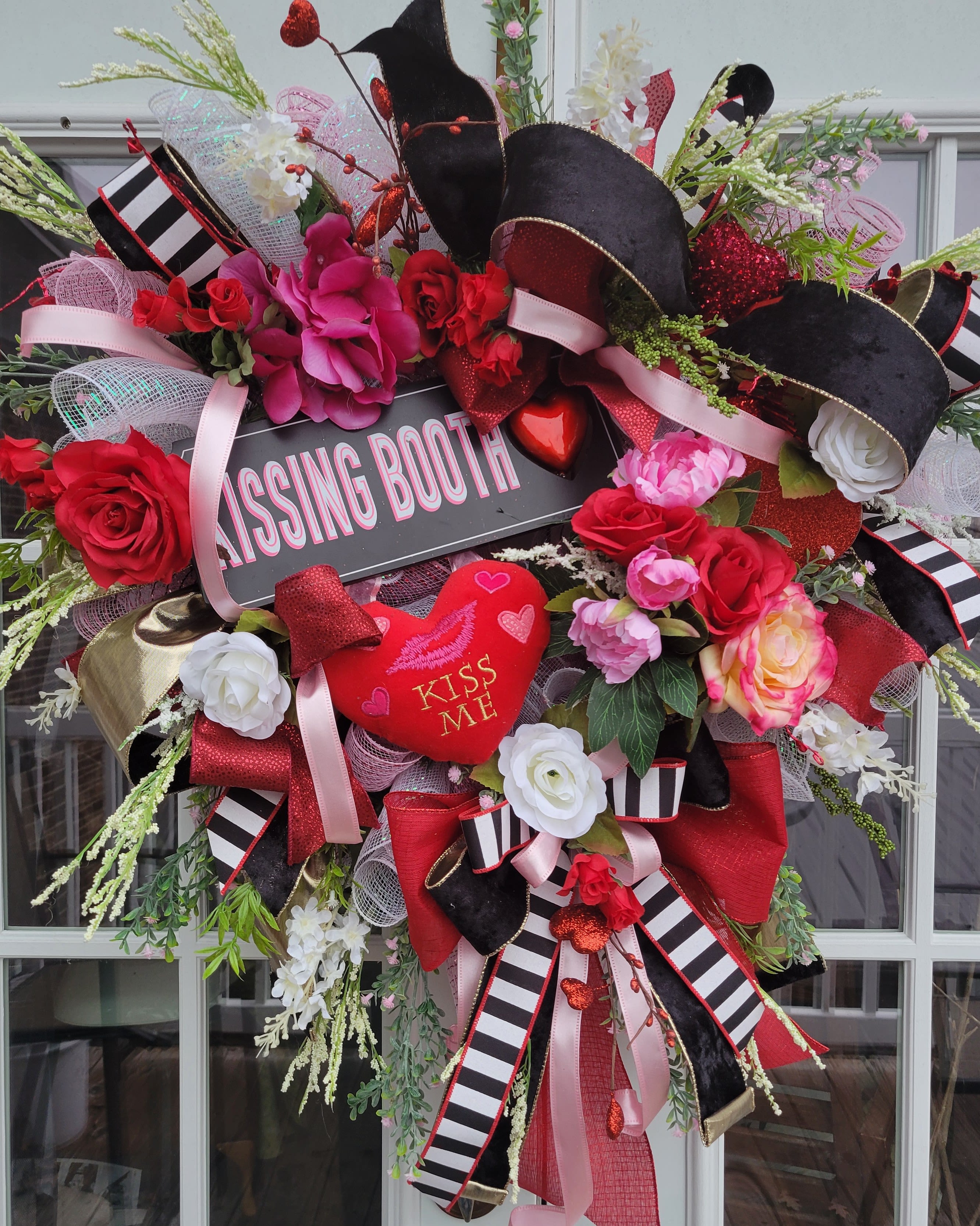 Heart-shaped floral wreath with red and pink roses and a "Kissing Booth" sign