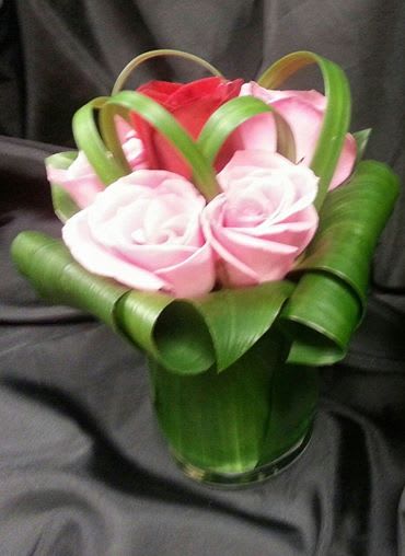 Small bouquet of pink and red roses wrapped with green ribbon loops